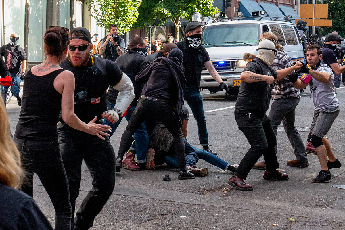 An injured member of antifa is dragged away from a brawl between the Proud Boys and far-left protesters during a white-nationalist march in Portland. Soon after, police declared the scene a riot and began to disperse the crowd. (Brendan Campbell/News21)